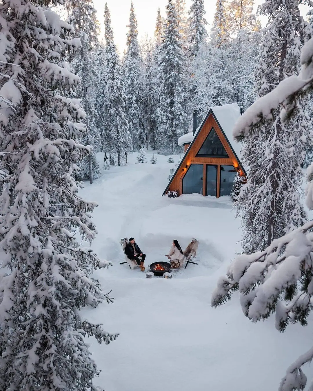 A forest cabin glowing warm in the forest at dusk.